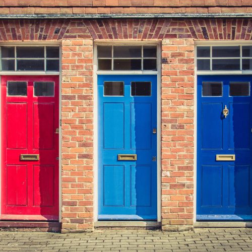Three,Differently,Coloured,Front,Doors,At,The,Entrance,Of,Old Composite Doors
